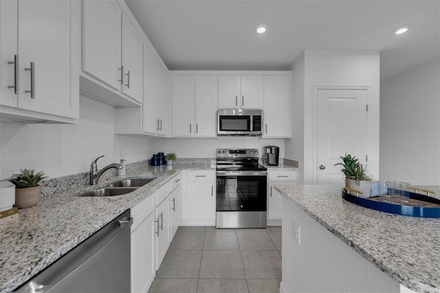 kitchen featuring sink, light tile patterned floors, stainless steel appliances, light stone countertops, and white cabinets