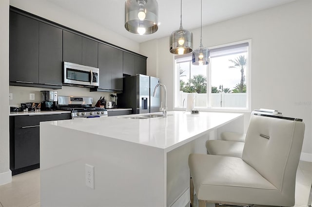 kitchen featuring decorative light fixtures, stainless steel appliances, a kitchen island with sink, and a breakfast bar area