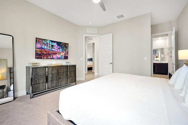 bedroom featuring light colored carpet, ensuite bath, and ceiling fan