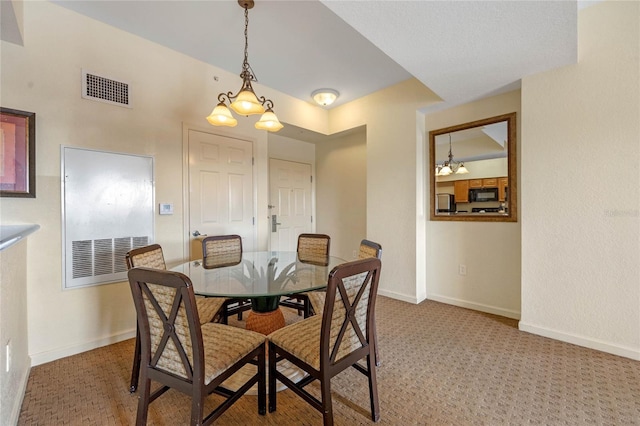 carpeted dining room with a chandelier