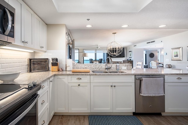 kitchen with sink, stainless steel appliances, light stone counters, dark hardwood / wood-style flooring, and white cabinets