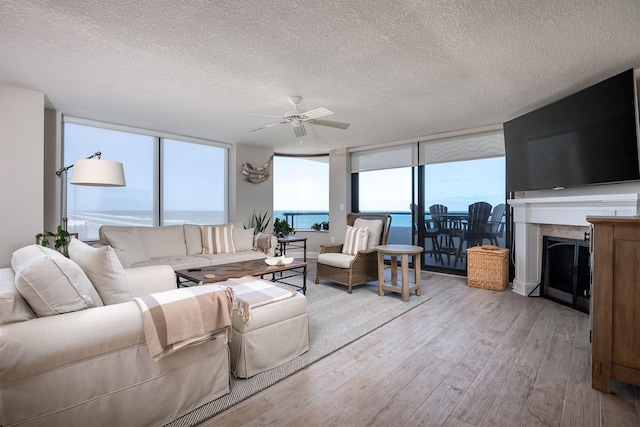 living room featuring a wall of windows, a textured ceiling, and light wood-type flooring