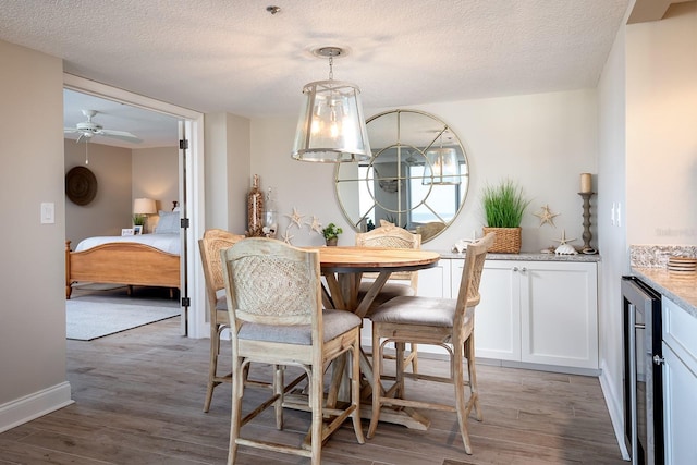 dining room with ceiling fan, wood-type flooring, a textured ceiling, and wine cooler