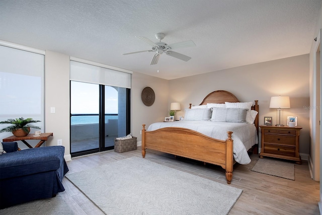 bedroom with access to exterior, a textured ceiling, light hardwood / wood-style floors, and ceiling fan