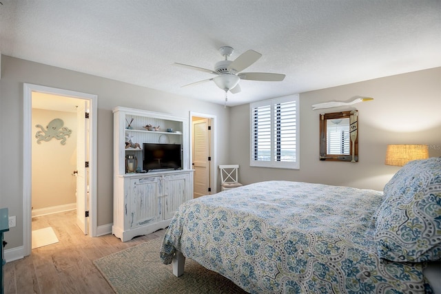 bedroom featuring a textured ceiling, light wood-type flooring, ensuite bathroom, and ceiling fan