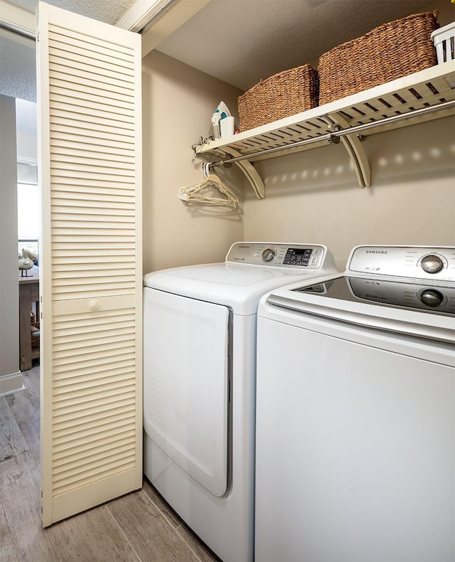 washroom featuring washer and dryer, a textured ceiling, and light wood-type flooring