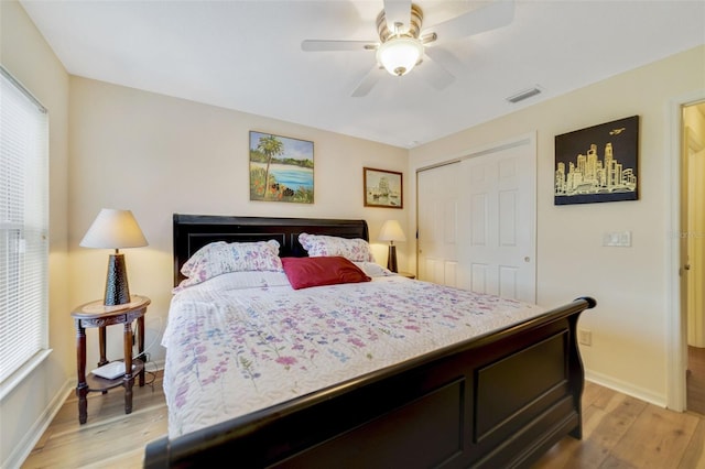 bedroom featuring multiple windows, ceiling fan, light wood-type flooring, and a closet