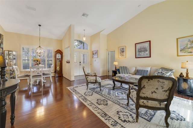 living room with dark wood-type flooring, a chandelier, high vaulted ceiling, and french doors