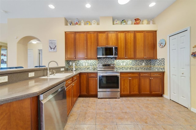 kitchen featuring stainless steel appliances, sink, light tile patterned floors, and backsplash