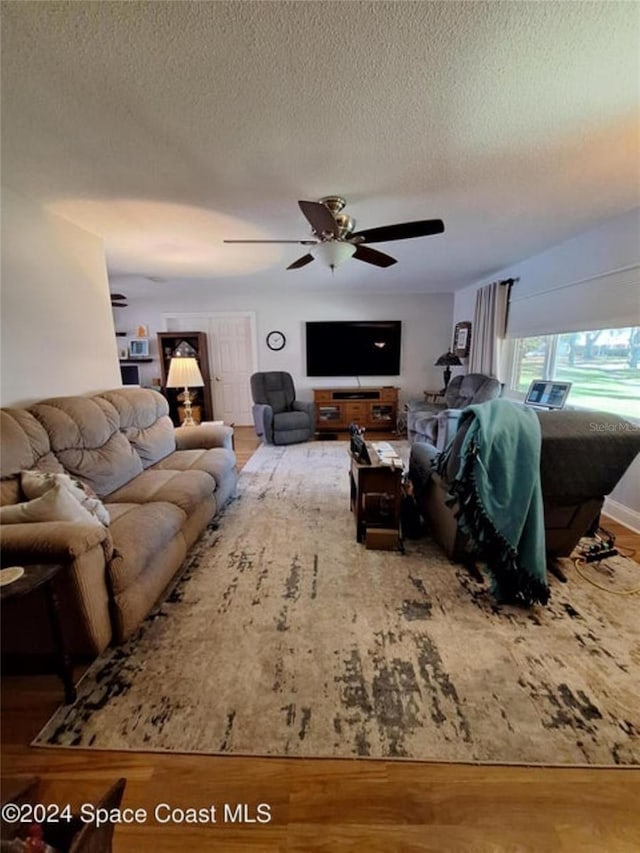 living room with hardwood / wood-style floors, a textured ceiling, and ceiling fan