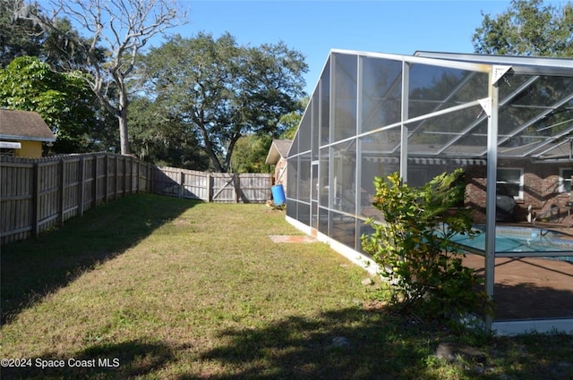 view of yard with a fenced in pool and glass enclosure