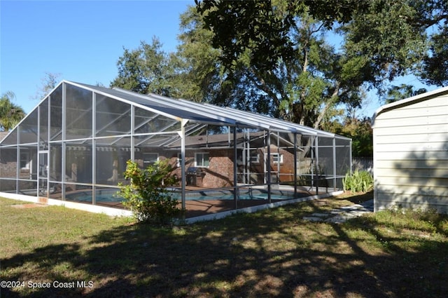 back of house with glass enclosure and a yard