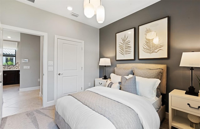 tiled bedroom featuring a notable chandelier and ensuite bath