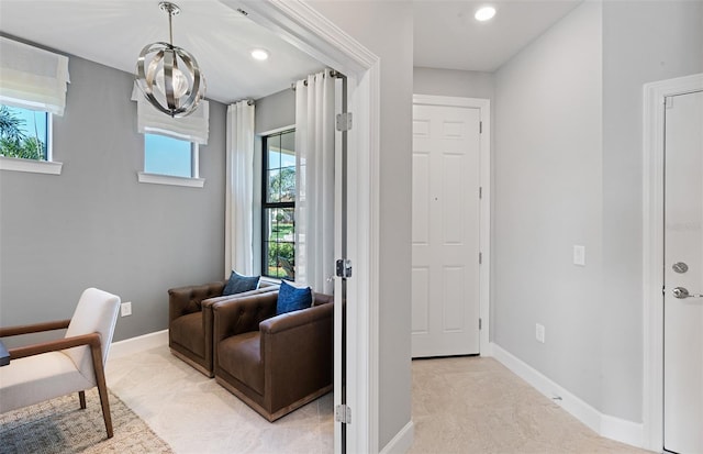 living area featuring a notable chandelier, a healthy amount of sunlight, and light colored carpet