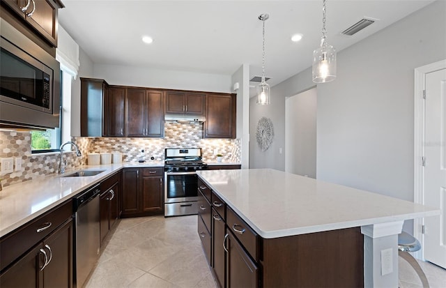 kitchen with decorative backsplash, stainless steel appliances, sink, a center island, and hanging light fixtures