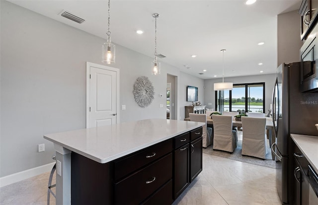 kitchen featuring a center island, a kitchen breakfast bar, stainless steel fridge, decorative light fixtures, and light tile patterned floors