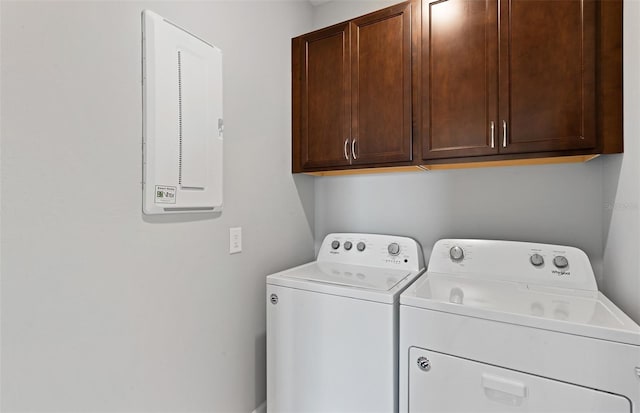 clothes washing area with cabinets and washer and dryer