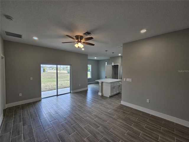 unfurnished living room featuring baseboards, wood tiled floor, visible vents, and a ceiling fan