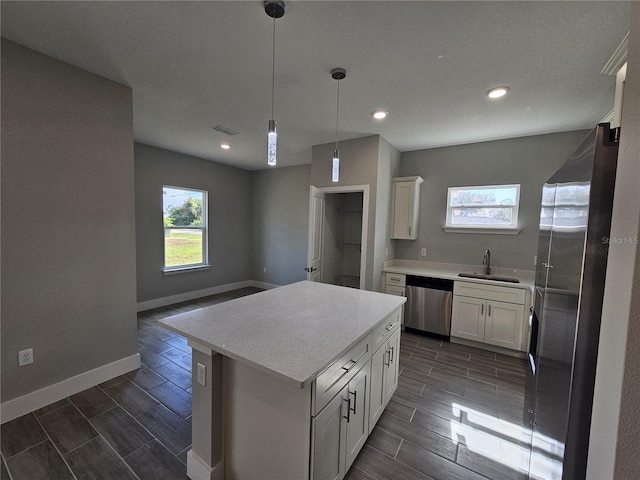 kitchen with baseboards, visible vents, stainless steel appliances, wood finish floors, and a sink