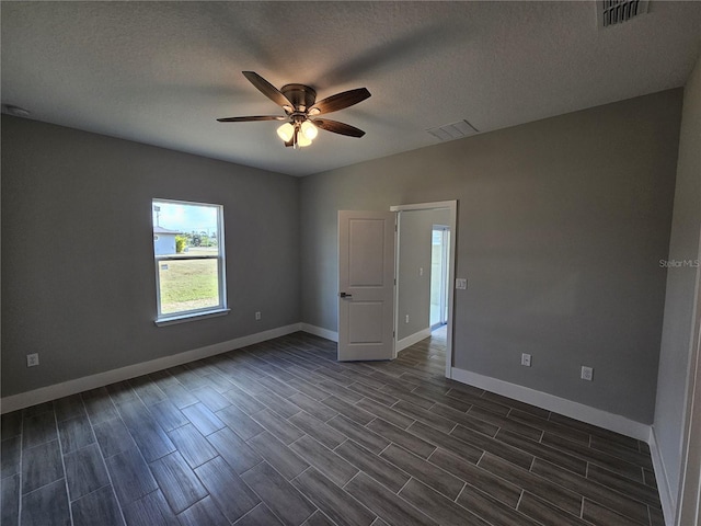 spare room featuring baseboards, visible vents, ceiling fan, and a textured ceiling