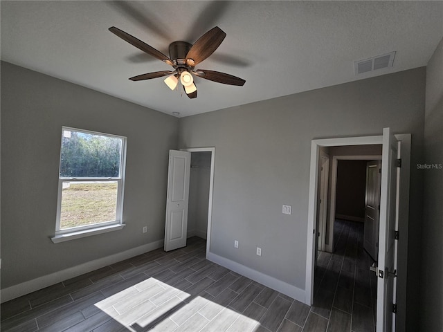 unfurnished bedroom with baseboards, a ceiling fan, visible vents, and wood tiled floor