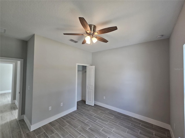 unfurnished bedroom featuring a closet, visible vents, wood tiled floor, ceiling fan, and baseboards