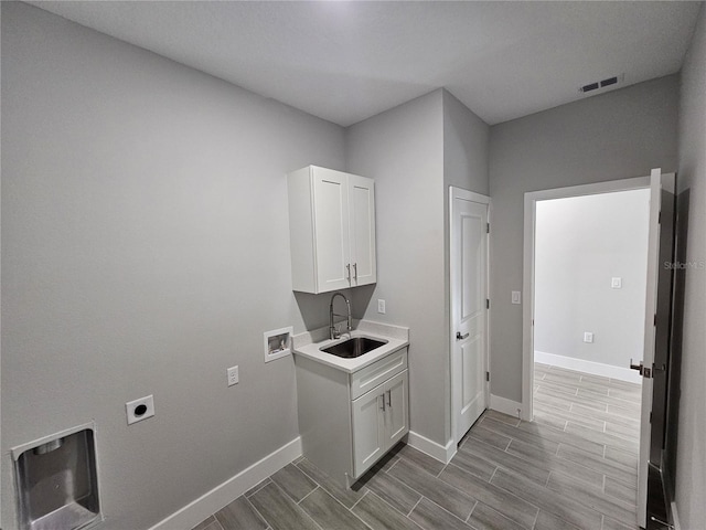 washroom featuring washer hookup, a sink, baseboards, cabinet space, and electric dryer hookup