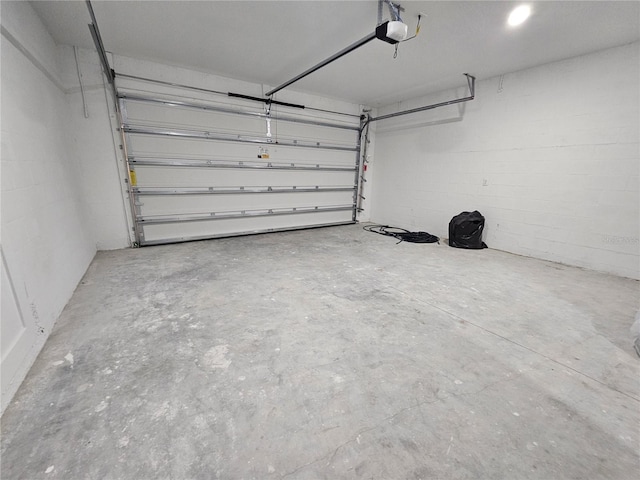 garage featuring concrete block wall and a garage door opener