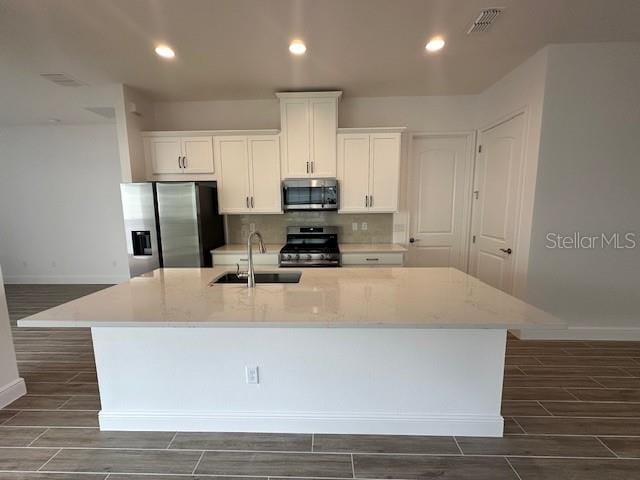 kitchen featuring white cabinetry, appliances with stainless steel finishes, sink, and a center island with sink