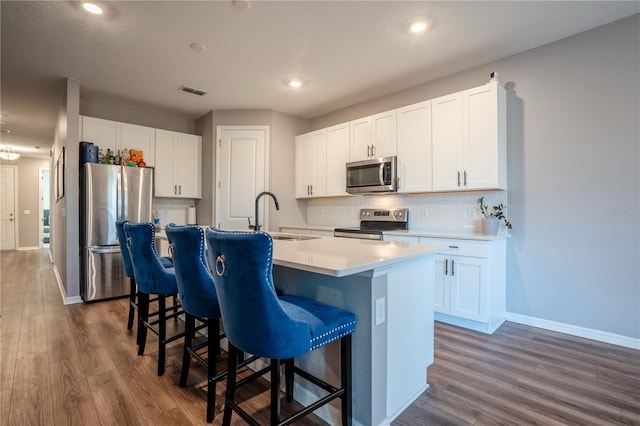 kitchen with an island with sink, stainless steel appliances, white cabinetry, and sink