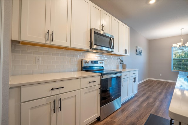 kitchen with pendant lighting, dark wood-type flooring, white cabinets, appliances with stainless steel finishes, and a chandelier