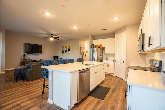 kitchen featuring stainless steel appliances, sink, wood-type flooring, a center island with sink, and white cabinets