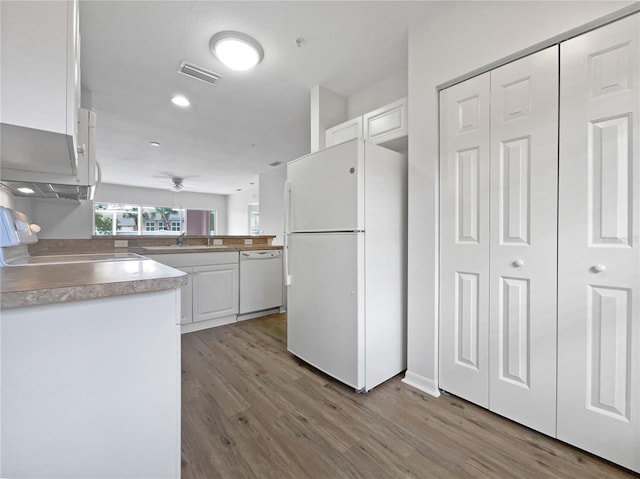 kitchen with white cabinets, white appliances, kitchen peninsula, and light hardwood / wood-style floors