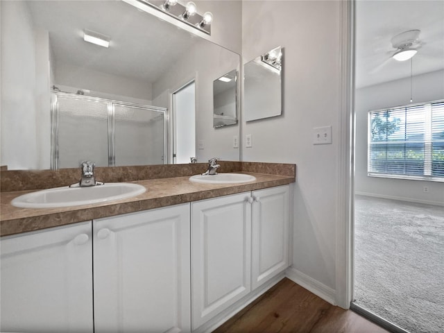 bathroom with hardwood / wood-style flooring, ceiling fan, walk in shower, and vanity