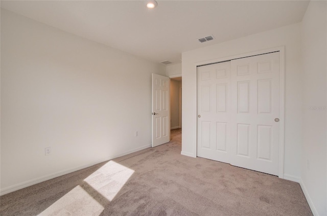 unfurnished bedroom featuring light carpet and a closet