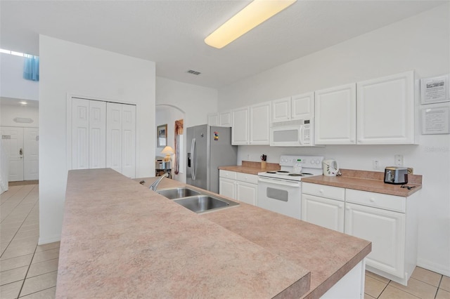 kitchen with white appliances, white cabinets, sink, light tile patterned floors, and an island with sink