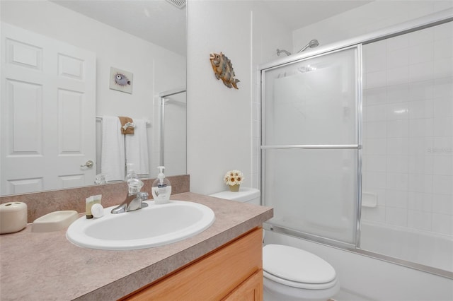 full bathroom featuring vanity, toilet, and shower / bath combination with glass door