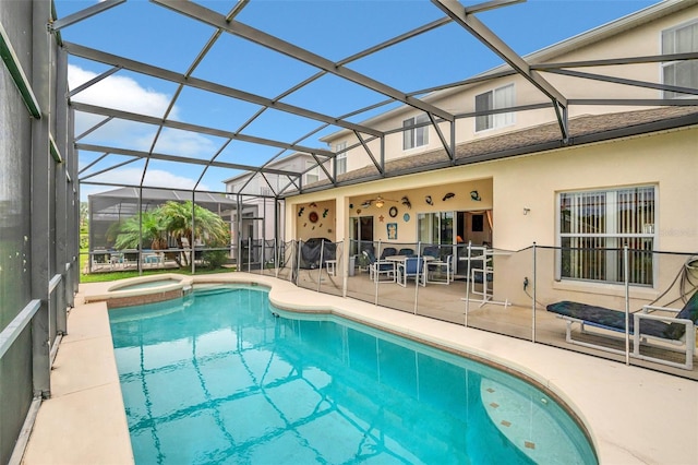 view of swimming pool with glass enclosure, ceiling fan, a patio area, and an in ground hot tub