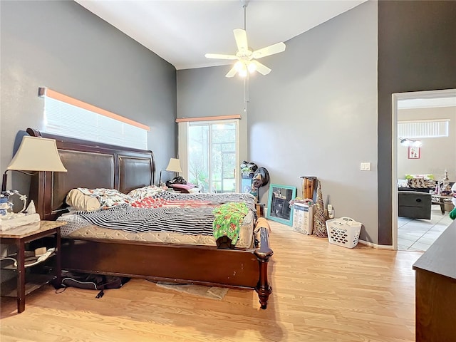 bedroom featuring light wood-type flooring, high vaulted ceiling, and ceiling fan