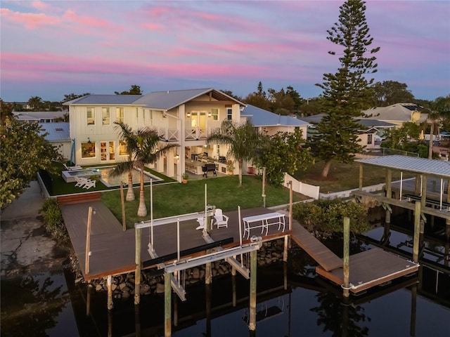 dock area with a lawn, a balcony, and a water view