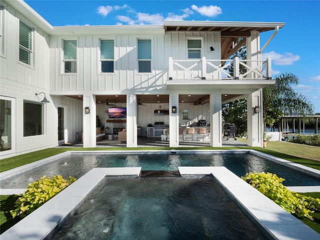 rear view of house with a pool with hot tub, a balcony, and a patio