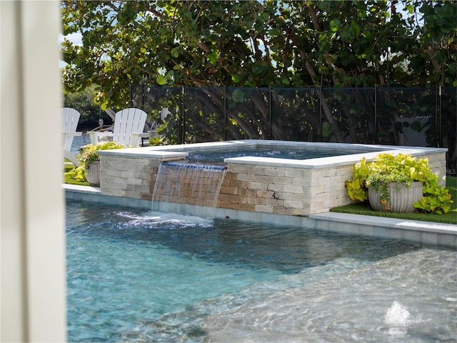 view of swimming pool featuring pool water feature and an in ground hot tub