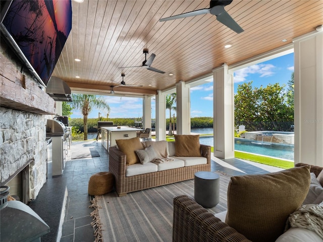 view of patio with grilling area, an outdoor kitchen, a water view, pool water feature, and an outdoor stone fireplace