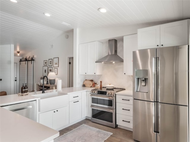 kitchen with white cabinetry, stainless steel appliances, wall chimney range hood, kitchen peninsula, and lofted ceiling