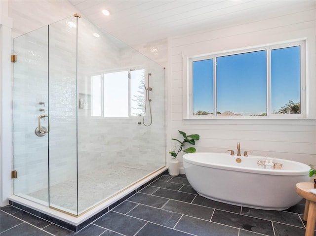 bathroom with tile patterned floors, wooden walls, and shower with separate bathtub