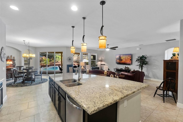 kitchen with stainless steel dishwasher, an island with sink, hanging light fixtures, and ceiling fan with notable chandelier