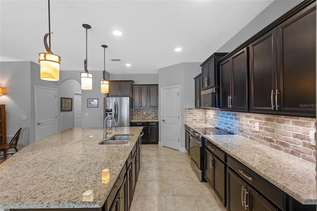 kitchen featuring sink, an island with sink, stainless steel appliances, and decorative light fixtures