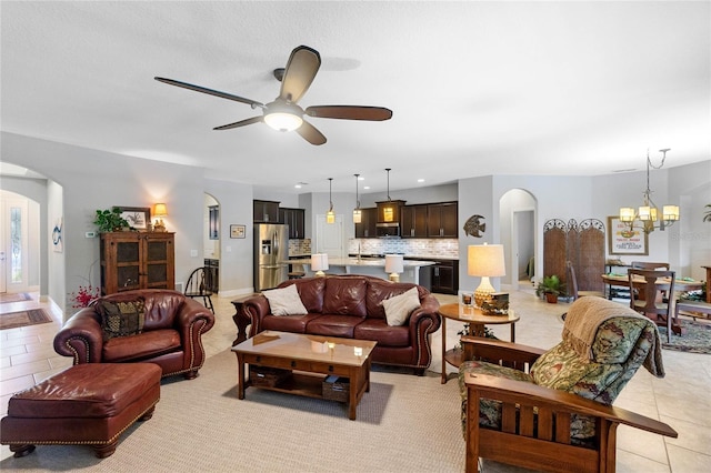 tiled living room featuring ceiling fan with notable chandelier