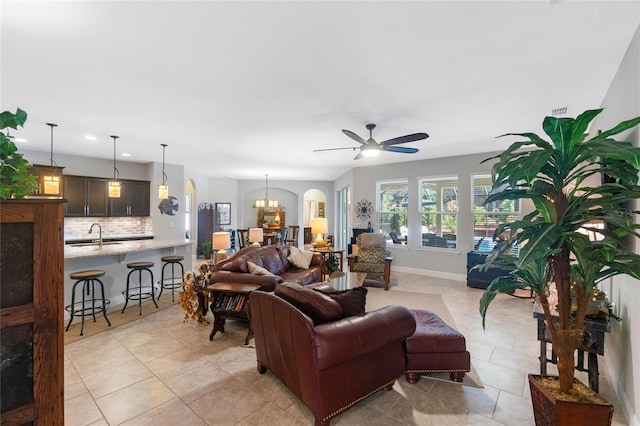 living room featuring sink, light tile patterned floors, and ceiling fan with notable chandelier