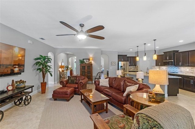 tiled living room featuring ceiling fan and sink